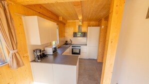 A compact kitchen with white cabinets, a central island, and a built-in oven. - Woody 1 - near ski resort at unique location (St. Georgen am Kreischberg)