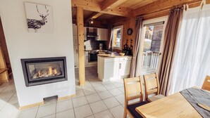 Ein gemütliches Blockhaushaus-Interieur mit Kamin, Holztisch und Küchenzeile.