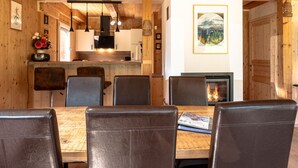 Un interior de madera con una mesa de comedor, sillas, chimenea y una zona de cocina.