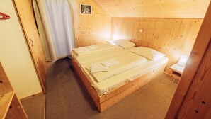 Une chambre à coucher aux murs lambrissés, avec un lit simple, une table de chevet et une petite table de nuit.