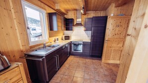 Une cuisine compacte avec des meubles en bois, un four encastré, un four à micro-ondes et un évier.