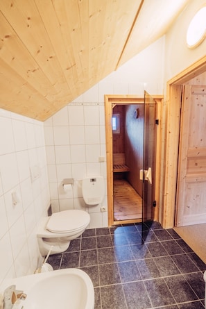 A bathroom with a wooden ceiling, a toilet, a bidet, and a shower area. - Woody 10 - cozy winter garden & sauna (St. Georgen am Kreischberg)