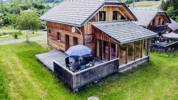 A wooden cabin with a balcony and outdoor seating area.