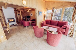 A cozy wooden interior with a fireplace, red furniture, and a view of the outdoors. - Woody 10 - cozy winter garden & sauna (St. Georgen am Kreischberg)