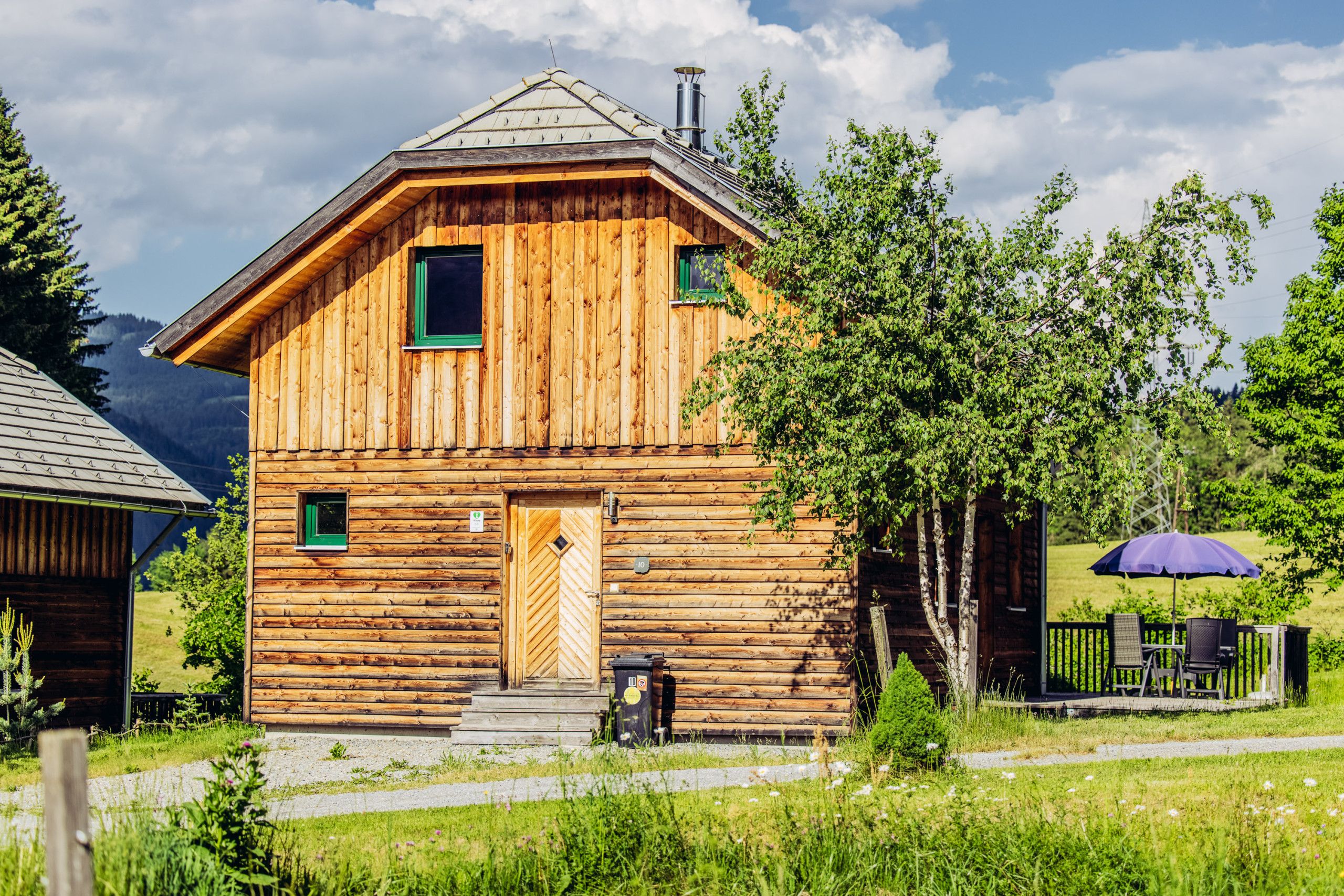 A wooden cabin with a front door, two windows, and a chimney.