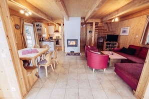Un intérieur de chalet chaleureux comprenant un coin repas, une cuisine, une cheminée et un espace détente.