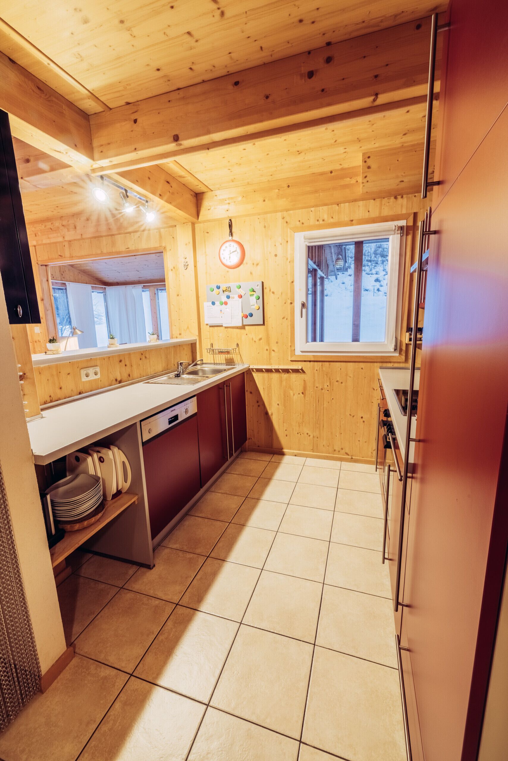 Un interior de madera con área de cocina, que incluye un lavamanos, armarios y una ventana.