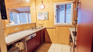 A wooden interior with a kitchen area, including a sink, cabinets, and a window. - Woody 12 - with sauna & 2 cozy terraces (St. Georgen am Kreischberg)