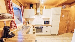 Cozinha compacta com armários brancos, micro-ondas, forno e máquina de café.