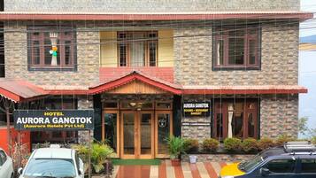 A hotel with a stone facade, multiple windows, and a sign indicating it offers rooms, restaurant, and banquet services.