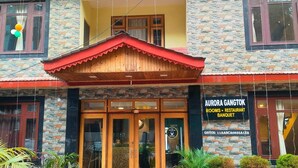 A hotel named "Aurora Gangtok" with a stone facade, wooden entrance, and a signboard indicating rooms, restaurant, and banquet services. - Aurora Gangtok (Gangtok)