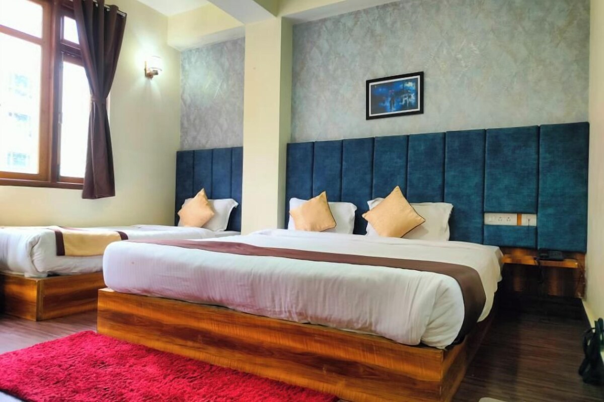 A hotel room with two beds, a red rug, a grey textured wall, and a framed picture.