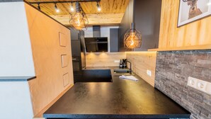 A modern kitchen with a black countertop, wooden accents, and pendant lighting. - Woody 17 - Hillside Chalet Kreischberg (St. Georgen am Kreischberg)