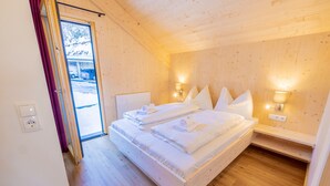 Een slaapkamer met houten lambrisering, twee bedden, een deur naar buiten en wandlampen.