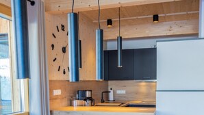 Une cuisine moderne avec des meubles en bois, un réfrigérateur en acier inoxydable et une table à manger en bois, assortie de chaises.