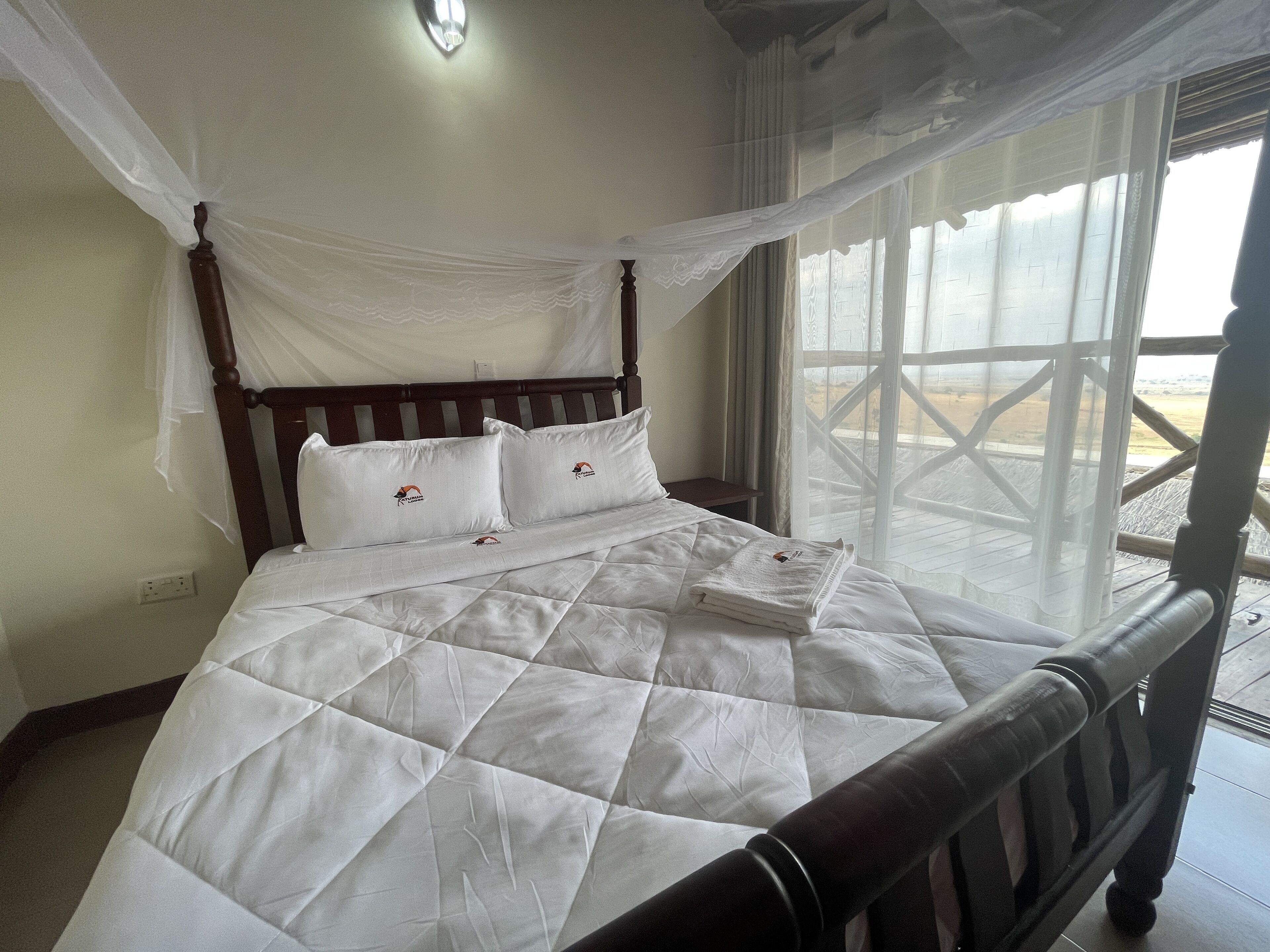 Una cama con colcha blanca, cabecera de madera y dosel.