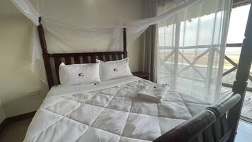 Una cama con colcha blanca, cabecera de madera y dosel.