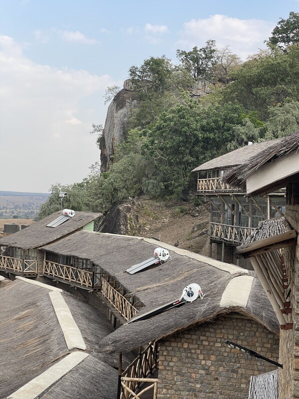A traditional building with thatched roofs and wooden railings, situated on a hillside with a view of the landscape.