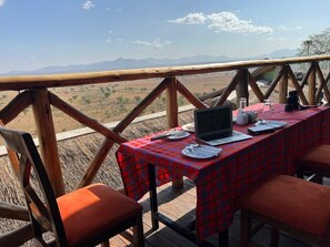 Enjoy a meal or work session in this outdoor dining area with a table for two, overlooking a breathtaking landscape.