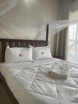 Restful retreat with a bed featuring a white quilted bedspread and two pillows, set against a wooden headboard.