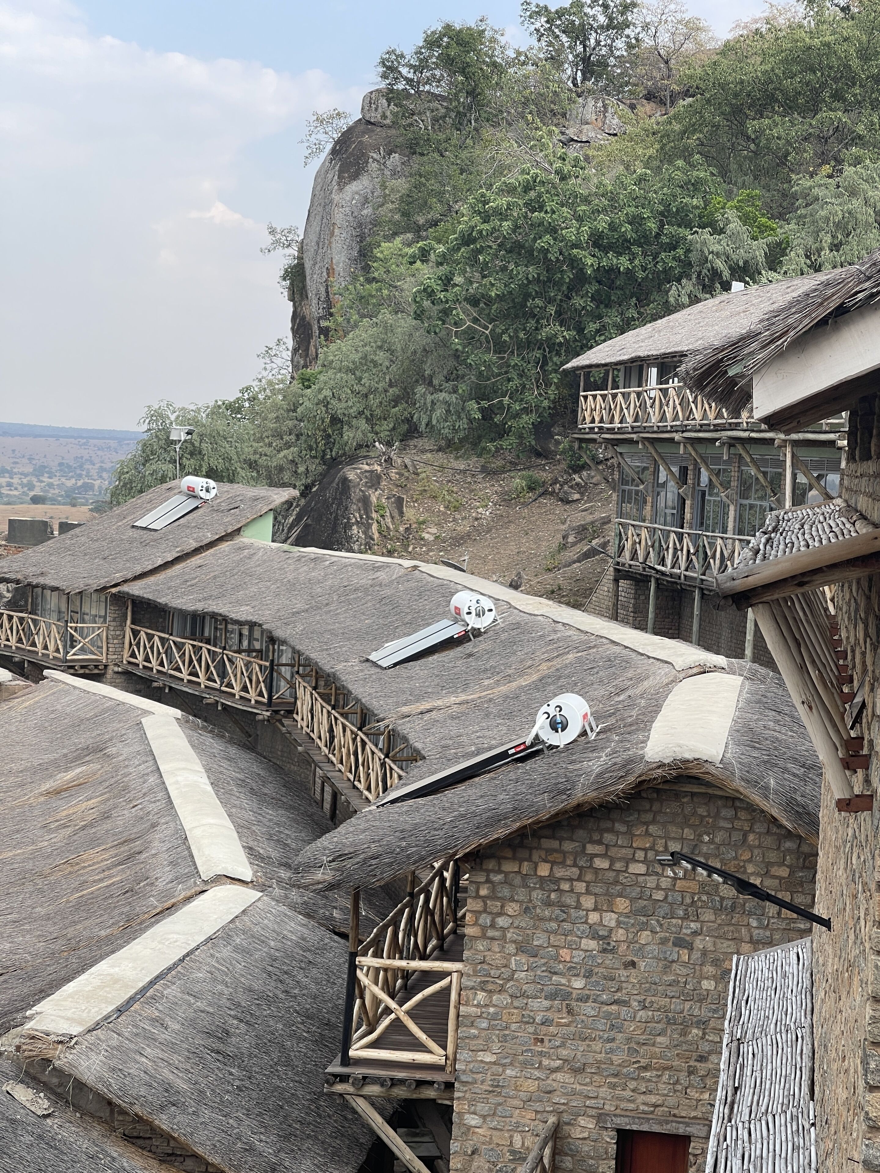 A traditional stone building with a thatched roof, wooden balconies, and satellite dishes.
