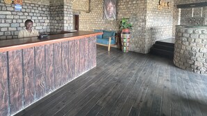 A reception area with a stone wall, wooden ceiling, and a reception desk. - Katurum Lodge Kidepo  (Loitanit)