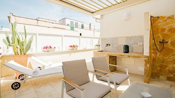 A sunlit patio with a seating area, a small kitchen, and a view of neighboring buildings. - Sirocco Suite with private terrace (Tuglie)