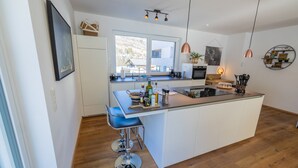 A modern kitchen with a central island, bar stools, and pendant lighting.