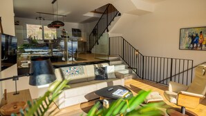 A modern living room with a sofa, coffee table, and a staircase leading to an upper level.