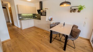 Une cuisine moderne avec des meubles blancs, un plancher en bois et un coin repas comprenant une table et des chaises.