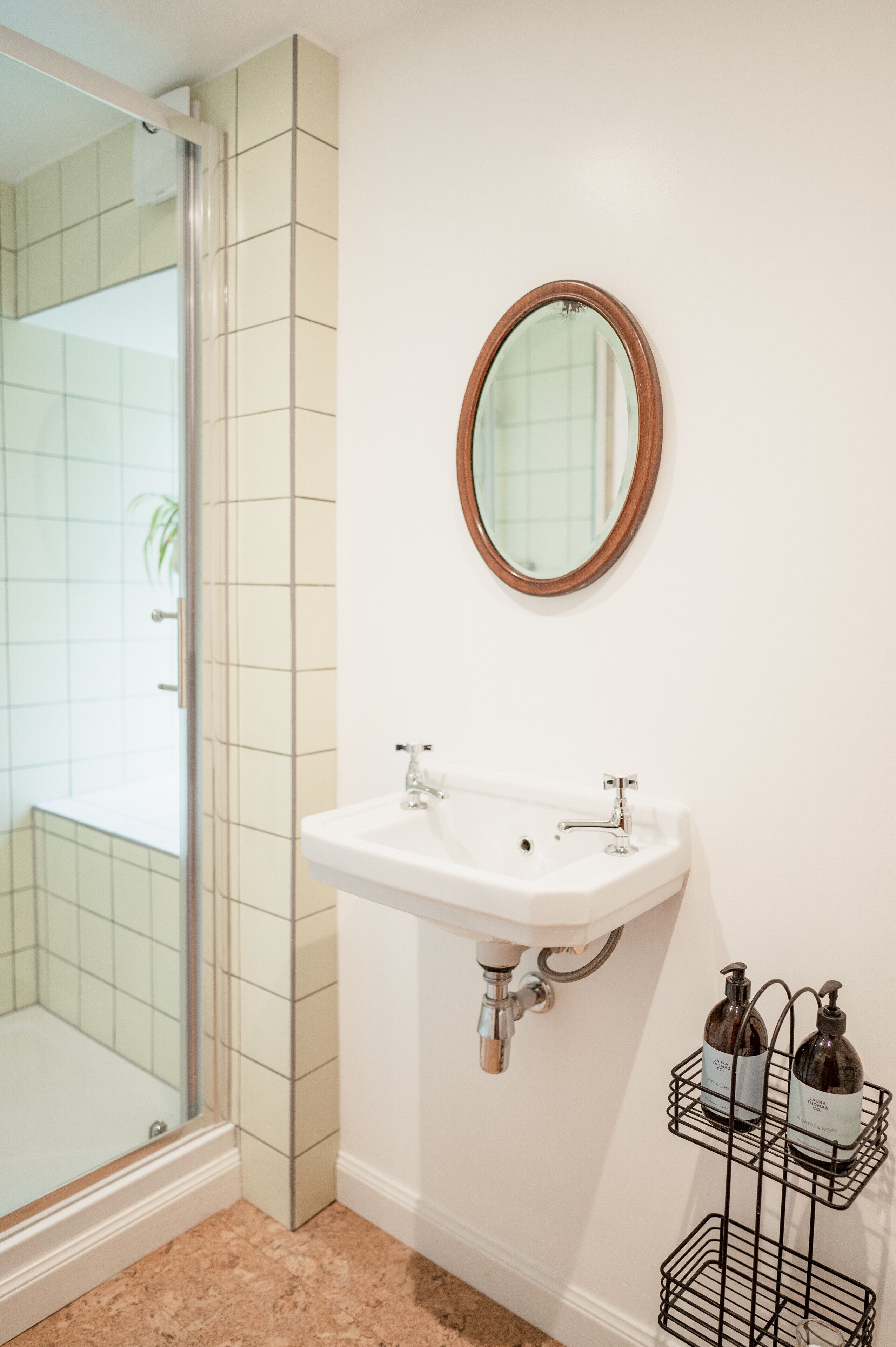 A bathroom with a white sink, a mirror, and a shower.