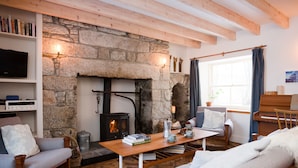 A cozy living room with a stone fireplace, wooden beams, a piano, and comfortable seating. - The Dell of Abernethy (Nethy Bridge)