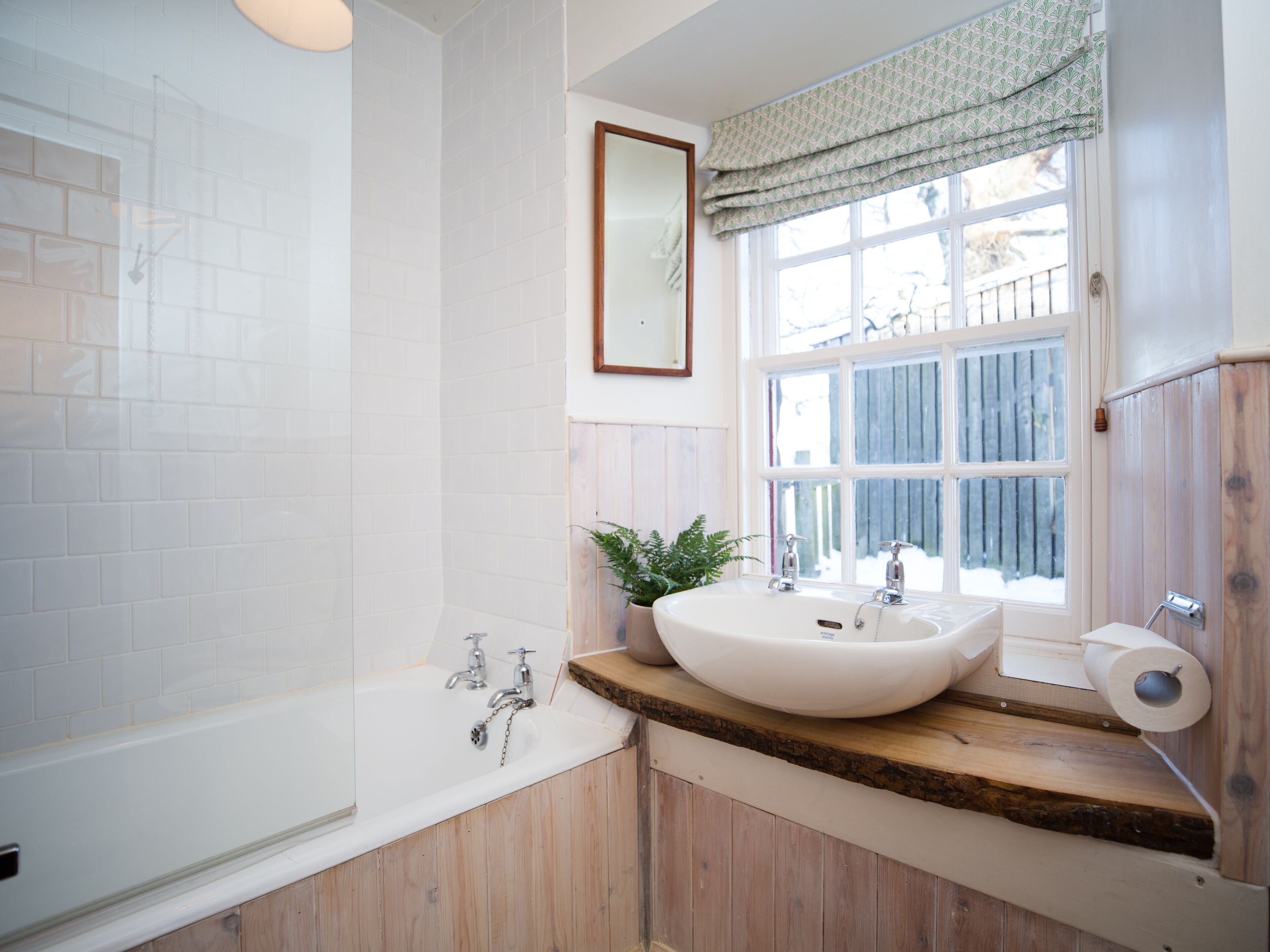Une salle de bain avec une baignoire, un lavabo, un miroir et une fenêtre.