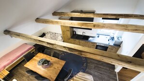 Une pièce de style loft comprenant un coin repas, une cuisine et un lit en mezzanine.