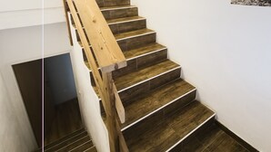 Un escalier en bois, doté d’une rampe, mène à l’étage supérieur.