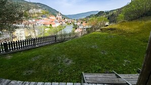 Blick auf eine Stadt am Flussufer, mit einer Holzterrasse im Vordergrund und dem Fluss.