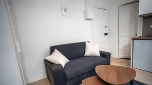 Un salón moderno con un sofá gris oscuro, dos cojines blancos y una pequeña mesa de centro de madera.