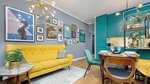 A modern living room with a yellow sofa, a round coffee table, and a dining area with a wooden table and chairs. - Stylish Apartment with 2 Bedrooms | Close to the Center, SmartTV (Warszawa)