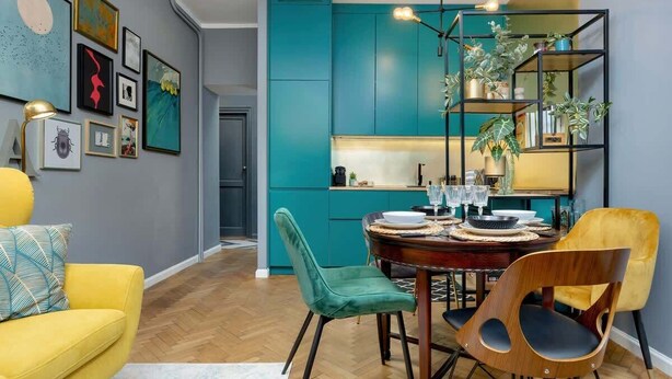 A modern dining area with teal cabinetry, a round wooden table, and green and yellow chairs. - Stylish Apartment with 2 Bedrooms | Close to the Center, SmartTV (Warszawa)