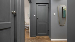 A hallway with grey walls, a wooden floor, and a closed door with a modern handle. - Stylish Apartment with 2 Bedrooms | Close to the Center, SmartTV (Warszawa)