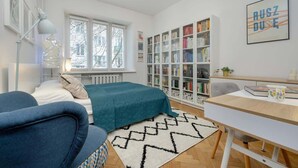 A modern bedroom with a bed, a desk, a bookshelf, and a window. - Stylish Apartment with 2 Bedrooms | Close to the Center, SmartTV (Warszawa)