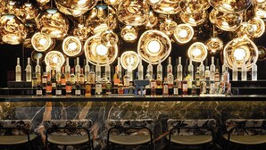 A bar area with a marble countertop, multiple liquor bottles, and patterned bar stools. - The Cloud One Gdansk (Gdansk)