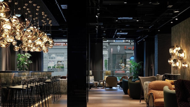 A modern interior with a bar area, seating, and a view of the street. - The Cloud One Gdansk (Gdansk)