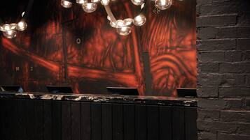 A bar area with a dark wooden counter, multiple laptops, and string lights.