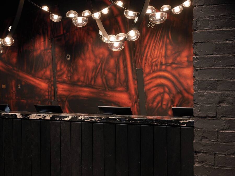 A bar area with a dark wooden counter, multiple laptops, and string lights.