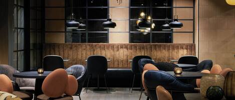 A modern interior with a wooden accent wall, black and orange seating, and pendant lighting.