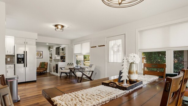 A modern kitchen with white cabinets, a dining area with a wooden table, and a cozy seating arrangement.