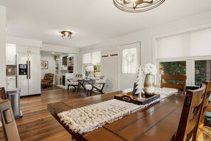 Una cocina moderna con armarios blancos, un comedor con mesa de madera y una zona de estar acogedora.