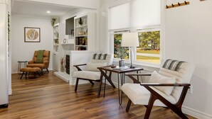 A living room with a fireplace, a dining table, and a view of the outdoors.