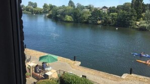 A view of a river with a dock and a table with an umbrella. - Beautiful Penthouse Apartment (Shepperton)